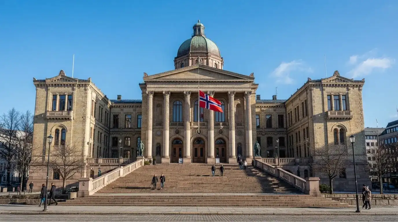 Fasade av en stor offentlig bygning i Oslo med brede trapper og et norsk flagg i vinden under klar himmel